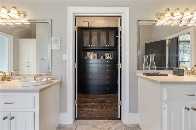 full bath with baseboards and two vanities