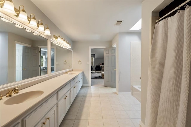 ensuite bathroom featuring tile patterned flooring, a sink, double vanity, and visible vents