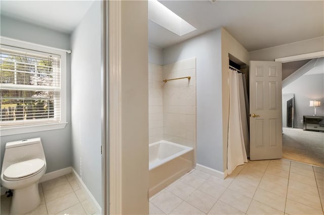 bathroom featuring tile patterned flooring, toilet, baseboards, a skylight, and shower / bath combo
