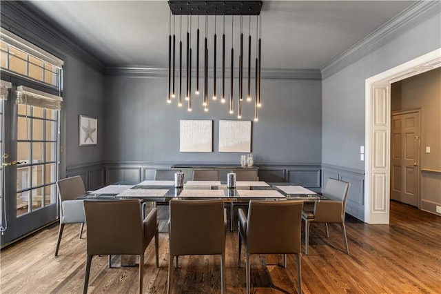dining area featuring a wainscoted wall, ornamental molding, and wood finished floors