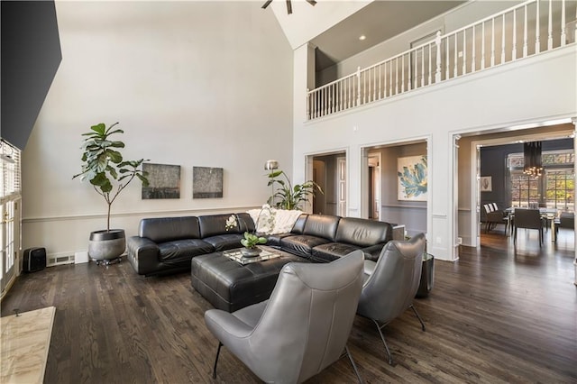 living area featuring a notable chandelier, visible vents, wood finished floors, and a towering ceiling