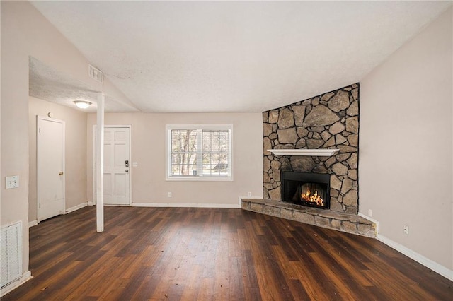 unfurnished living room with hardwood / wood-style flooring, baseboards, visible vents, and a stone fireplace