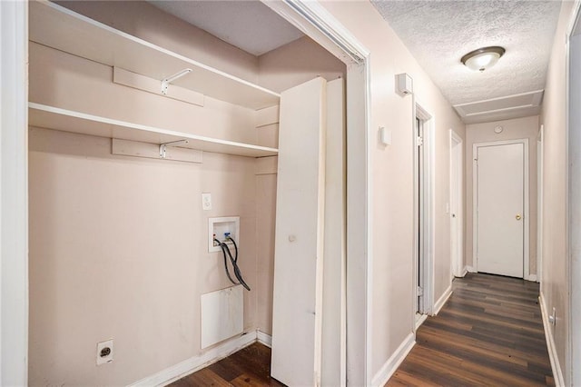 clothes washing area with dark wood-style floors, hookup for a washing machine, a textured ceiling, laundry area, and baseboards