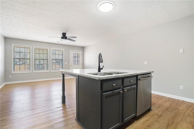 kitchen with dishwasher, an island with sink, light wood-style flooring, open floor plan, and a sink