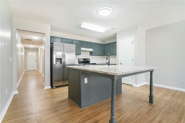 kitchen featuring stainless steel appliances, light wood-style floors, a sink, and under cabinet range hood