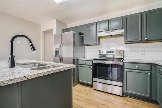 kitchen featuring a sink, under cabinet range hood, light wood-style flooring, and electric stove