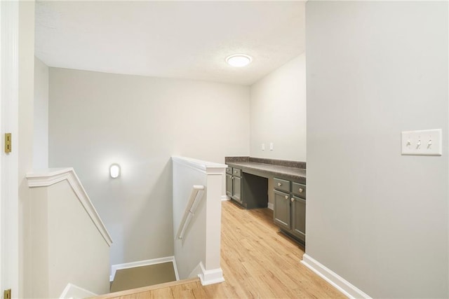 interior space with light wood finished floors, baseboards, and an upstairs landing