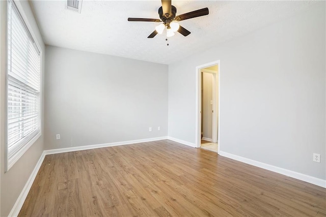 spare room featuring baseboards, visible vents, ceiling fan, and light wood finished floors