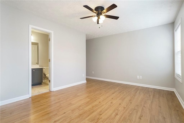 spare room featuring light wood finished floors, plenty of natural light, and baseboards