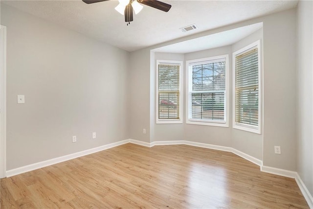 unfurnished room featuring baseboards, a ceiling fan, visible vents, and light wood-style floors