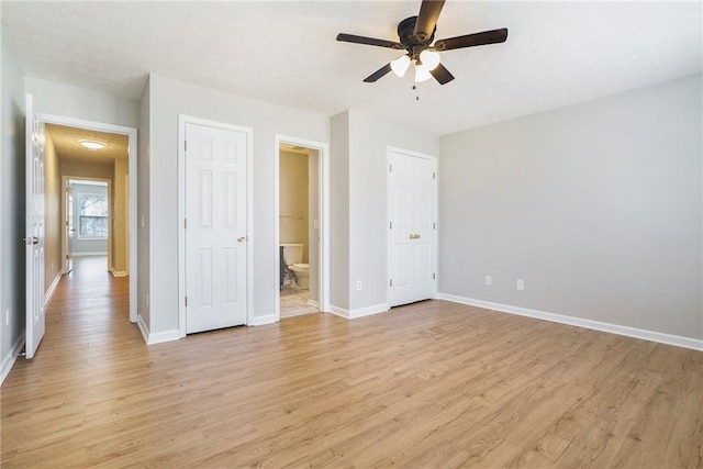 unfurnished bedroom with light wood-style floors, ensuite bath, and baseboards