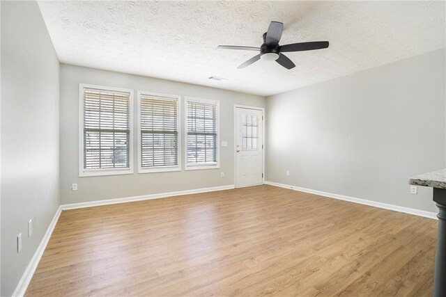 unfurnished room featuring baseboards, a textured ceiling, and light wood-style floors