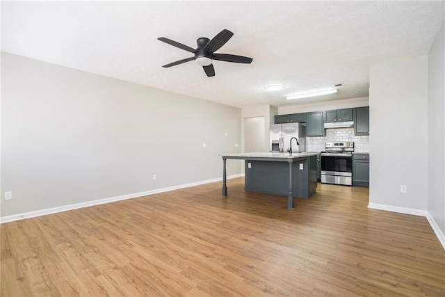 kitchen with tasteful backsplash, a kitchen breakfast bar, stainless steel appliances, light countertops, and under cabinet range hood