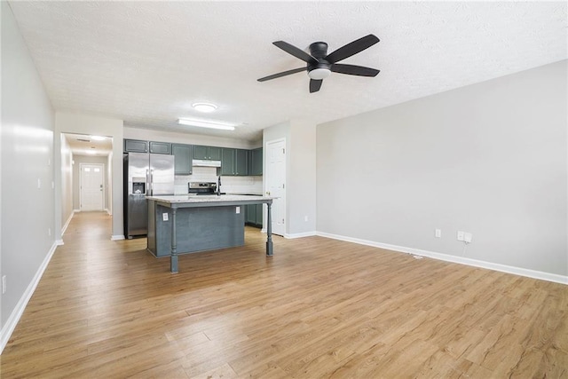 kitchen featuring a breakfast bar area, under cabinet range hood, stainless steel appliances, light countertops, and light wood finished floors