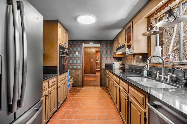 kitchen with glass insert cabinets, under cabinet range hood, decorative backsplash, black appliances, and a sink