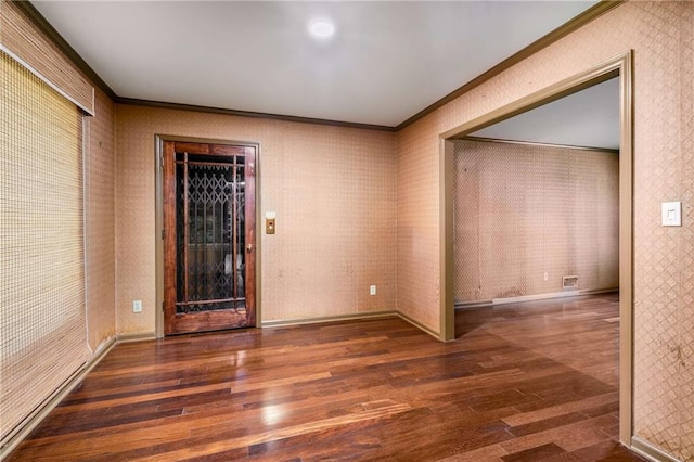 spare room featuring wallpapered walls, wood finished floors, baseboards, and ornamental molding