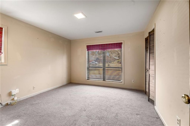 carpeted empty room with visible vents and baseboards