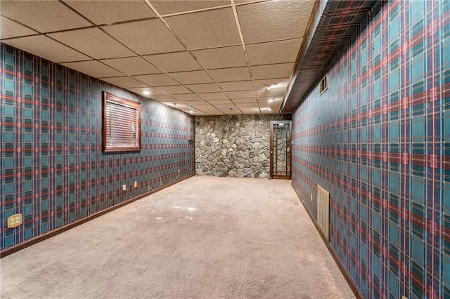 finished basement with wallpapered walls, a paneled ceiling, baseboards, and carpet floors