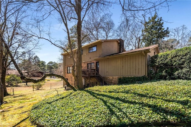 back of house featuring stairs, fence, and brick siding