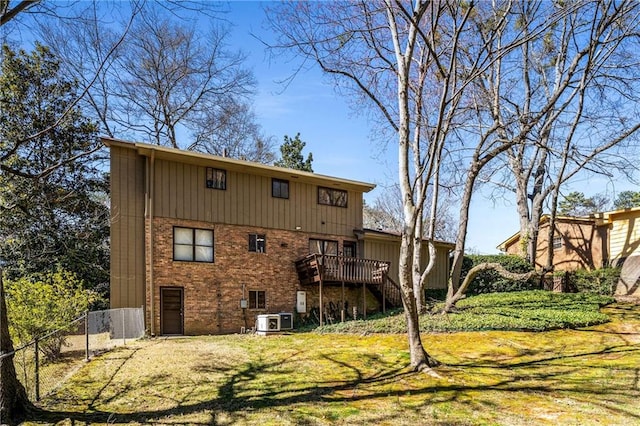 back of property featuring fence, cooling unit, a yard, a wooden deck, and brick siding