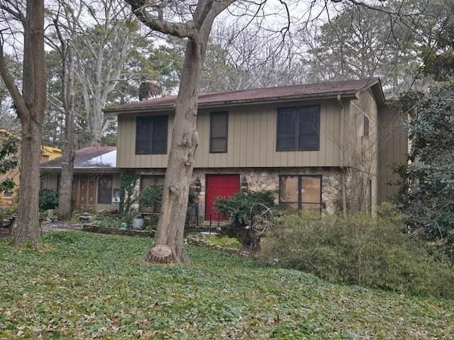 view of front of house with a front lawn, stone siding, and a chimney