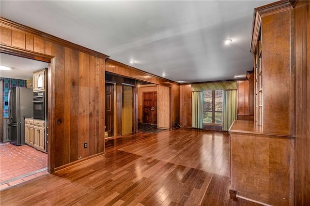 unfurnished room featuring crown molding, wooden walls, and wood finished floors