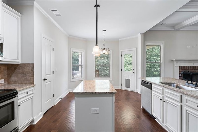 kitchen with light stone countertops, white cabinets, appliances with stainless steel finishes, a kitchen island, and sink