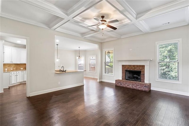 unfurnished living room featuring plenty of natural light, beam ceiling, and coffered ceiling