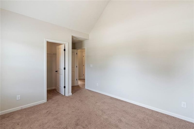 unfurnished bedroom with a spacious closet, light colored carpet, a closet, and lofted ceiling