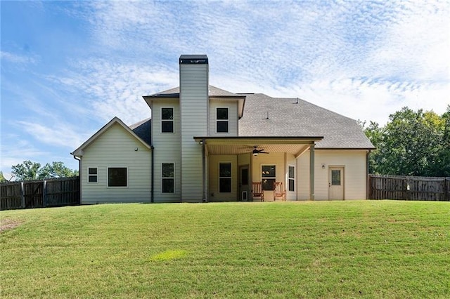 back of house with ceiling fan and a yard