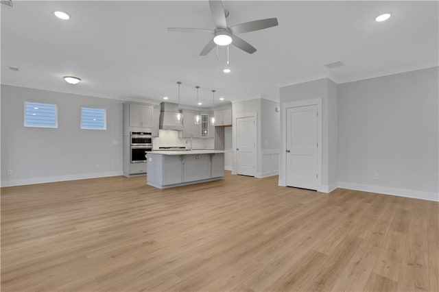 unfurnished living room featuring light wood-type flooring, ceiling fan, and sink