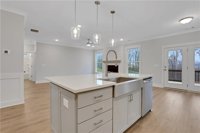 kitchen with white cabinetry, hanging light fixtures, light hardwood / wood-style flooring, dishwasher, and an island with sink