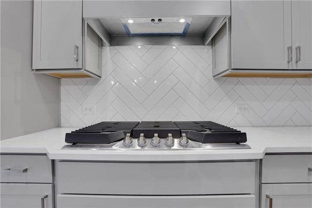 kitchen with backsplash, gray cabinets, and wall chimney range hood