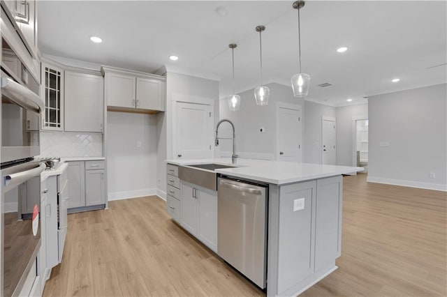 kitchen with pendant lighting, sink, appliances with stainless steel finishes, a kitchen island with sink, and decorative backsplash