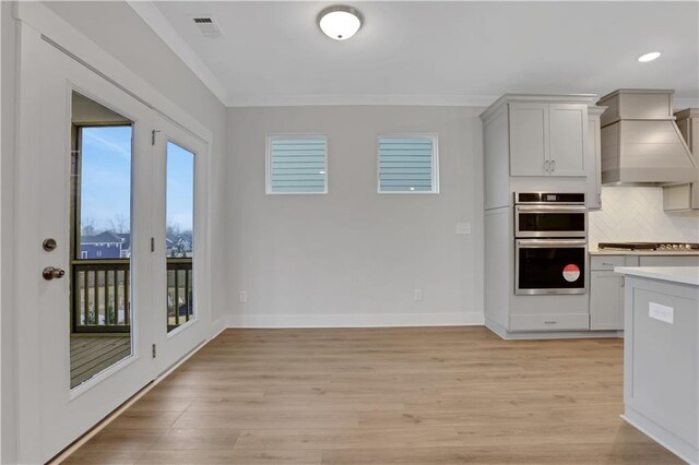 entryway featuring a wealth of natural light, crown molding, and light hardwood / wood-style floors