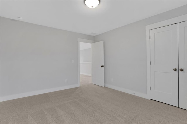 unfurnished bedroom featuring light colored carpet and a closet