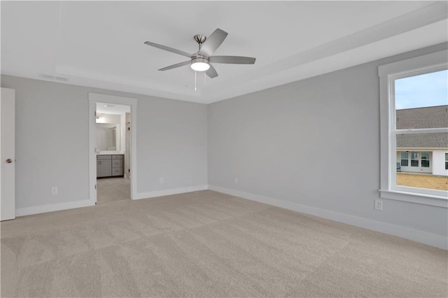 unfurnished bedroom with connected bathroom, light colored carpet, and ceiling fan