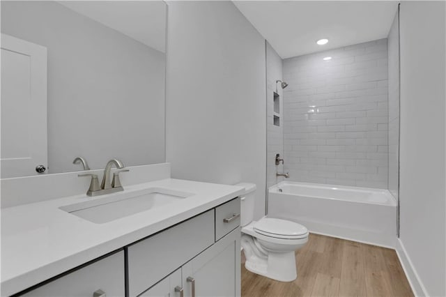 full bathroom featuring tiled shower / bath, wood-type flooring, toilet, and vanity