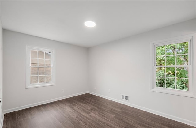 spare room with dark hardwood / wood-style flooring and a wealth of natural light