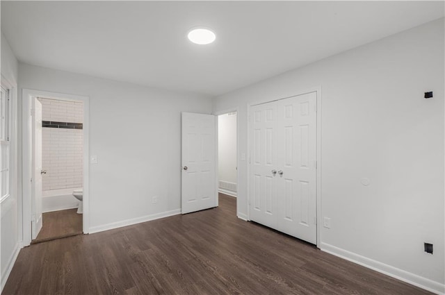 unfurnished bedroom featuring dark hardwood / wood-style floors, ensuite bathroom, and a closet