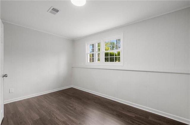 spare room featuring dark wood-type flooring and crown molding