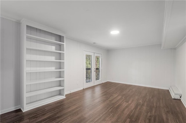 spare room featuring built in shelves, ornamental molding, and dark wood-type flooring