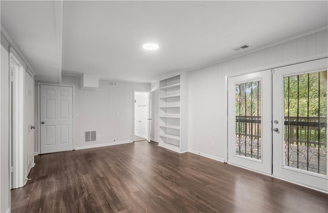 unfurnished living room with crown molding, dark hardwood / wood-style floors, built in features, and french doors