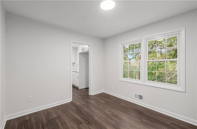 unfurnished bedroom with dark hardwood / wood-style floors and ensuite bathroom