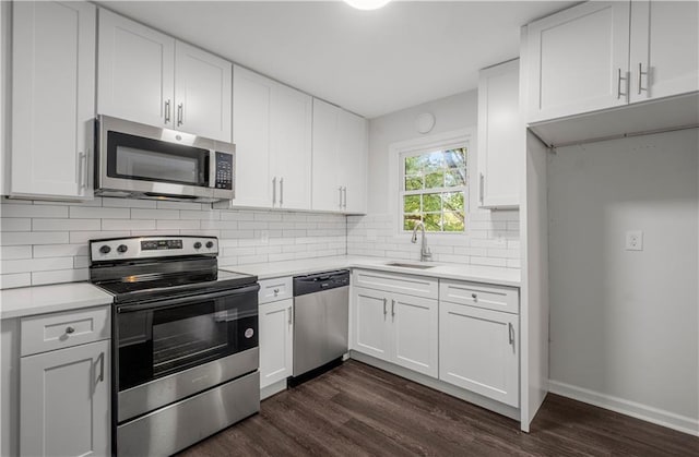 kitchen featuring sink, white cabinetry, stainless steel appliances, dark hardwood / wood-style floors, and decorative backsplash