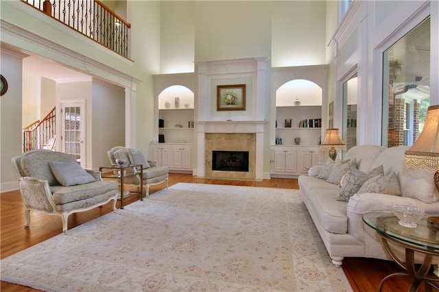 living room featuring light hardwood / wood-style floors, a high ceiling, and built in shelves