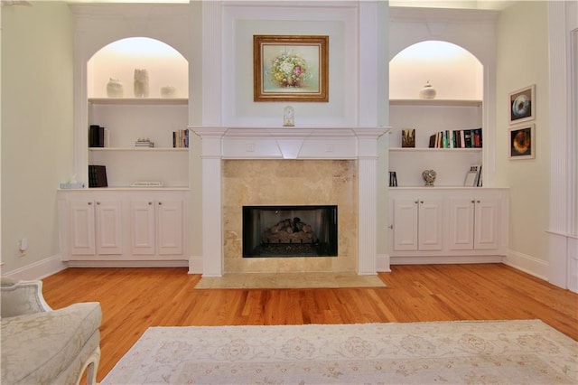 living room with light hardwood / wood-style flooring, a tile fireplace, and built in features