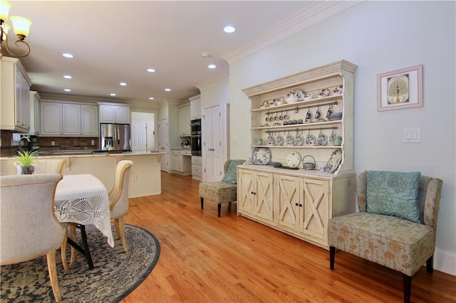 dining area with sink, crown molding, and light hardwood / wood-style flooring