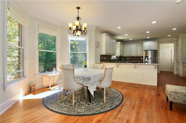 dining space with a wealth of natural light, ornamental molding, light hardwood / wood-style flooring, and an inviting chandelier