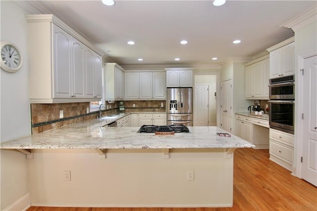 kitchen with kitchen peninsula, a breakfast bar area, white cabinetry, stainless steel appliances, and light hardwood / wood-style flooring